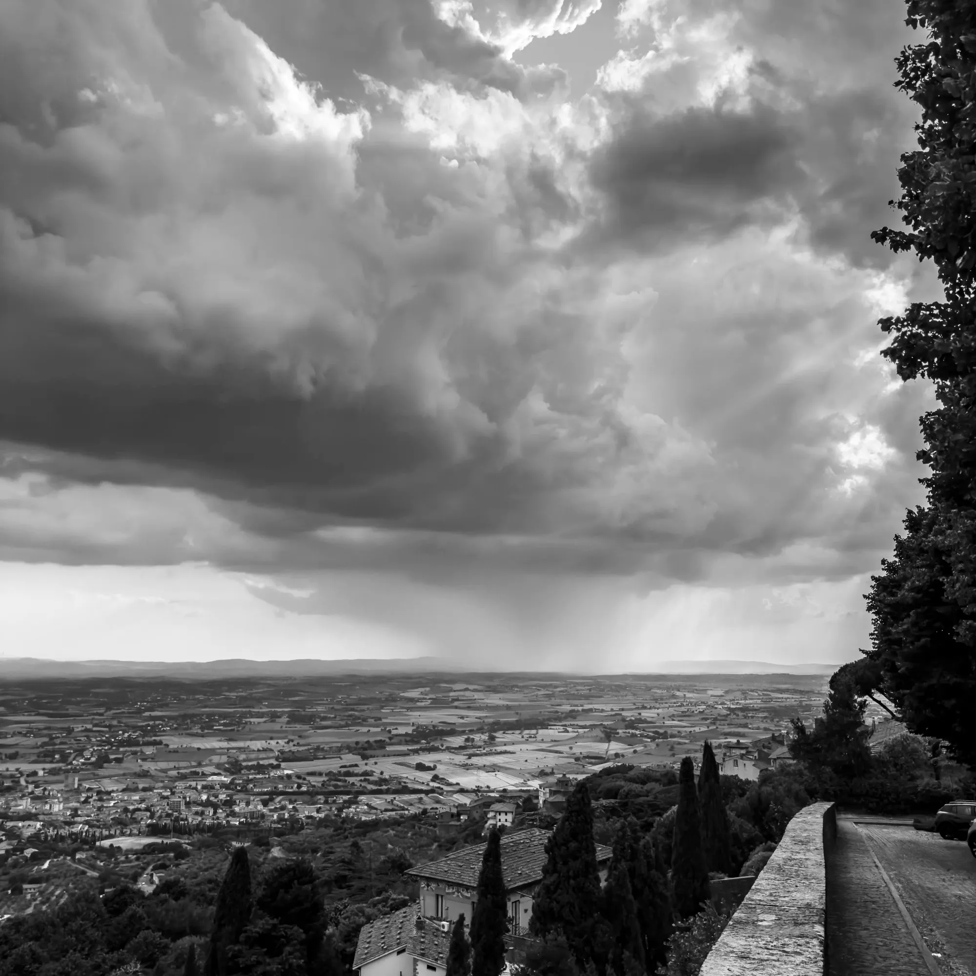 Monochromatic digital photograph of a rainstorm on the horizon, as seen from Cortona, Italy. 